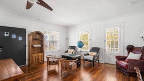 A room with hardwood flooring, a wooden bookcase, a globe, a leather armchair, and a dining table. - 7BR w/ Ocean Views + Onsite Parking + Central A/C (Ventnor City)