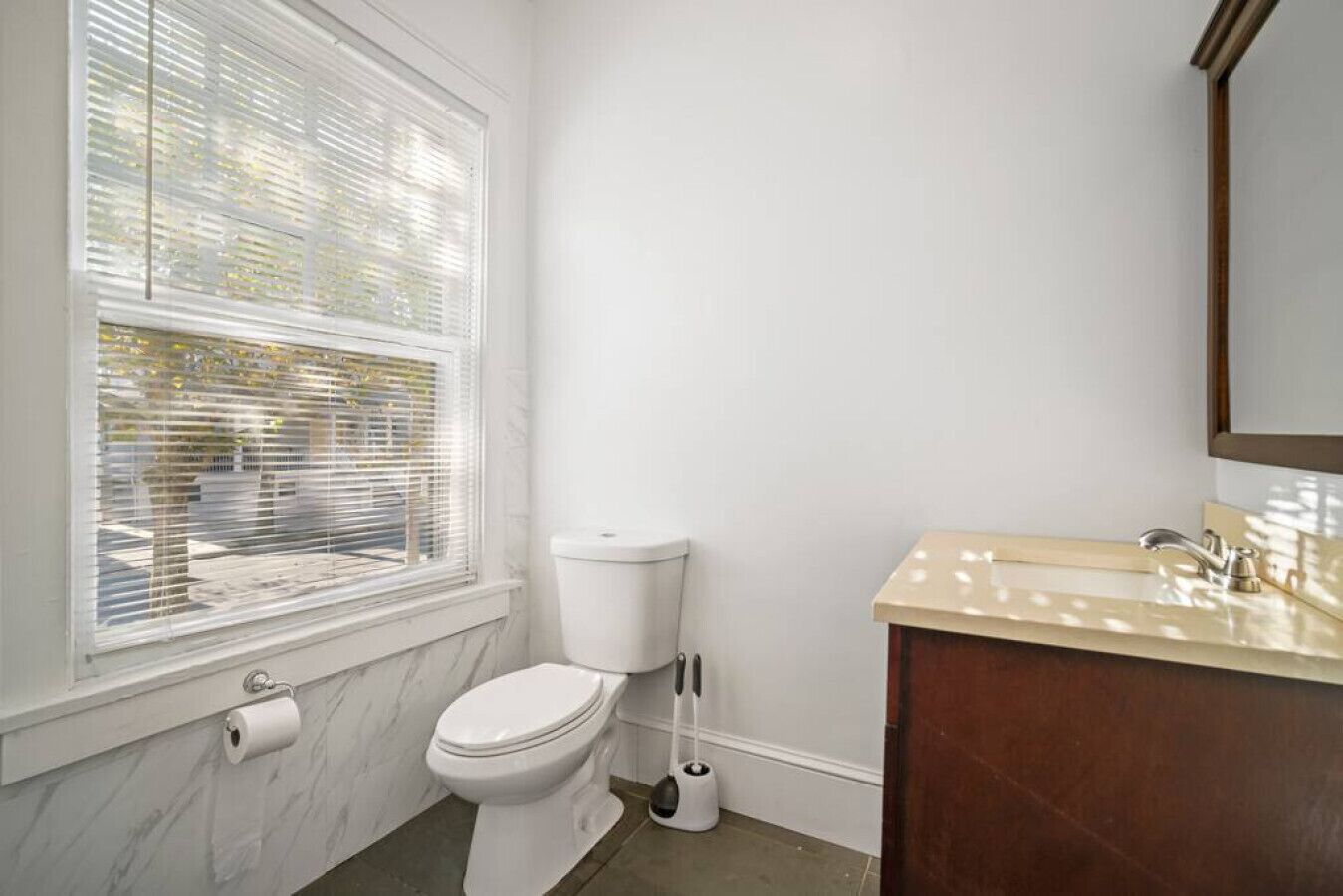 Een badkamer met toilet, wastafel en een raam met zonwering.