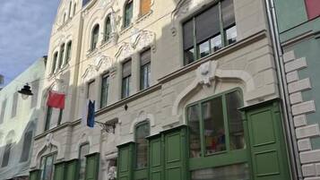A historic building with ornate architectural details, green shutters, and a visible storefront.