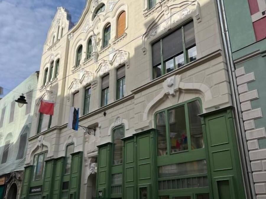 A historic building with ornate architectural details, green shutters, and a visible storefront.