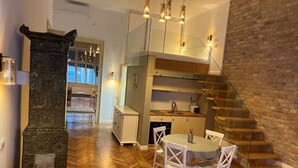 A modern kitchen with a dining area, a staircase, and a decorative fireplace. - VISAJ Downtown (Timisoara)