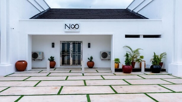 A modern hotel entrance with a white facade, a sign reading "NOO Boutique Hotel," and a paved courtyard with potted plants. - No. 8 Boutique Hotel (Ilorin)