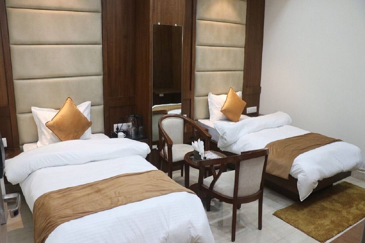A hotel room with two beds, a wooden chair, and a small table.