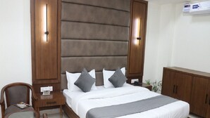 A bedroom with a large bed, a nightstand, a chair, and a wardrobe. - Signum CityScapes The Royal Jewel (Hisar)