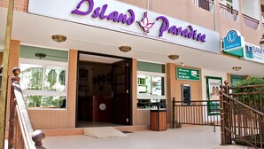 Exterior del Island Paradise Inn con un letrero que indica servicio de cajero automático las 24 horas.