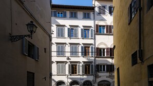 Une rue étroite bordée d’immeubles à étages, dotés d’arcs au-dessus des fenêtres et de volets.