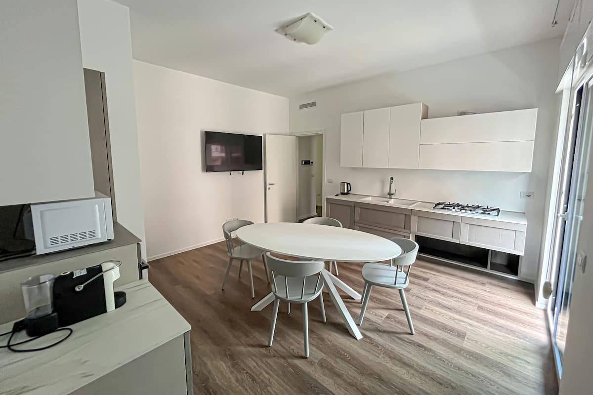 A modern kitchen with white cabinets, a built-in stove, and a large window.