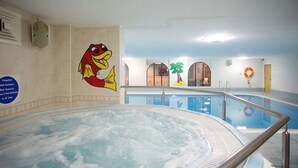 A swimming pool area with a hot tub, a mural of a fish, and a lifebuoy on the wall.