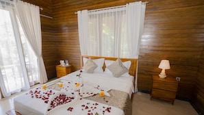 Un dormitorio con paneles de madera, una cama, mesitas de noche y una ventana con cortinas.