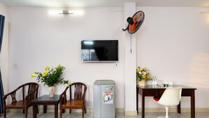 A dining area with a table, chairs, a refrigerator, and a TV mounted on the wall. - Loc Phat Hotel (Ho Chi Minh City)