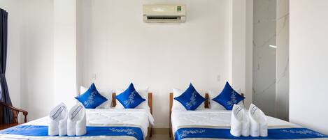 A hotel room with two beds, white bedding, blue pillows, and towels.