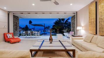 A modern living room with a sofa, a red chair, a coffee table, and a view of the outdoor patio area.
