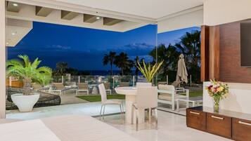 A modern living room with a large glass door leading to a balcony overlooking the ocean.
