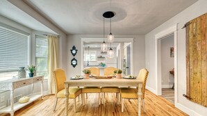 Een eetruimte met een houten tafel, vier stoelen en hangende hanglampen.