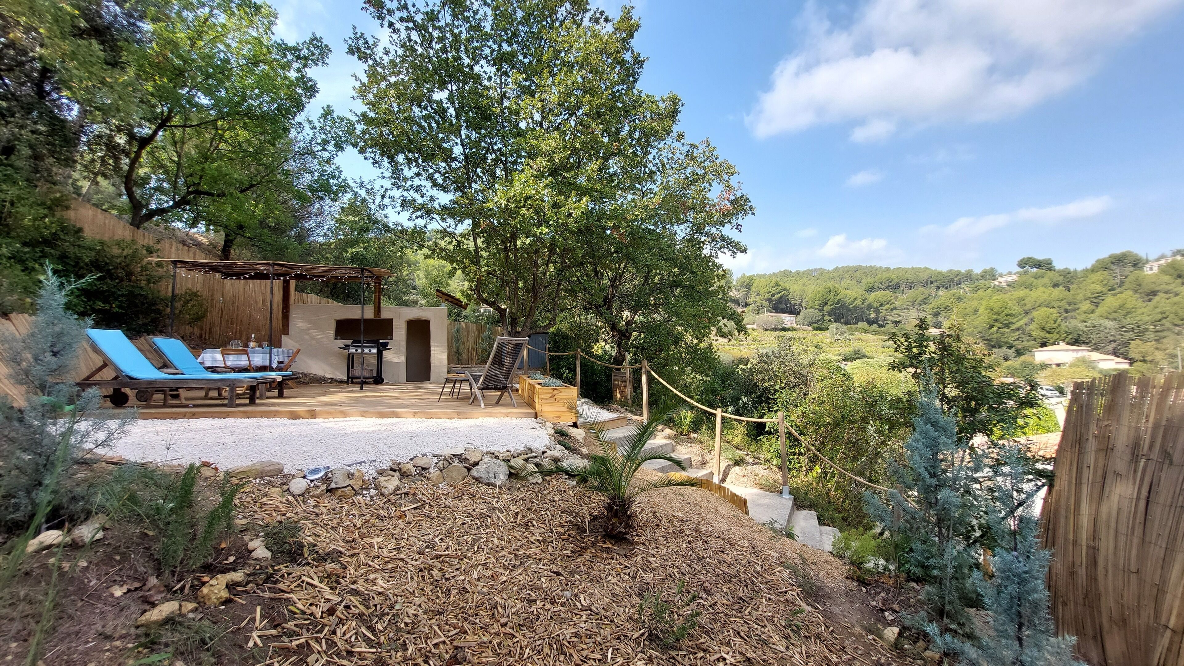 Eine Terrasse mit Grill, Liegestühlen und einer Pergola.