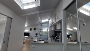 Moderni keittiö, jossa on kattovalokuvioita, ruokailutila ja suuri peili.