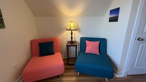A room with two sofas, one red and one blue, a small table with a lamp, and a door. - Budget friendly, fun, great location & clean! You found your next vacation home. (Surfside Beach)