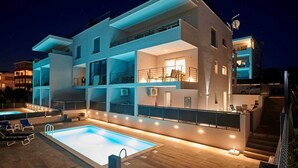 A modern multi-story building with a rooftop pool, outdoor seating, and a staircase leading to the upper levels.