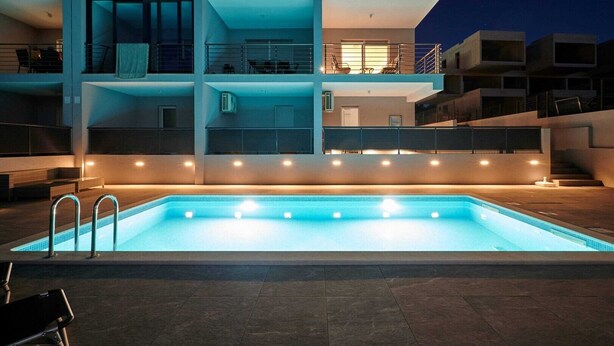 A modern building with a swimming pool, multiple balconies, and outdoor seating areas.