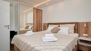 A modern hotel room with a large bed, a wooden headboard, and a mirror.