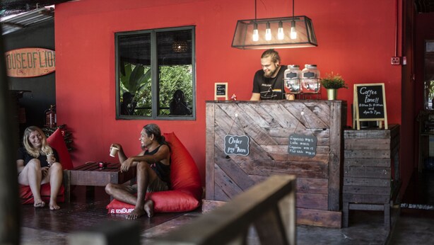A cozy cafe with a red interior, a wooden counter, and a sign indicating coffee time. - House of Lion Hostel and Guesthouse (Langkawi)