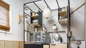 Een kleine keuken met een zwart-wit kleurenschema, houten kastjes en een rond vloerkleed.