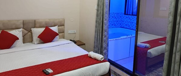 A hotel room with a bed, a red quilt, a white pillow, and a red pillow.