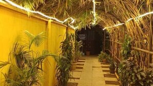 A pathway lined with potted plants and a yellow wall, leading to a dark area beyond. - Igatpuri Hill Retreat (Igatpuri)