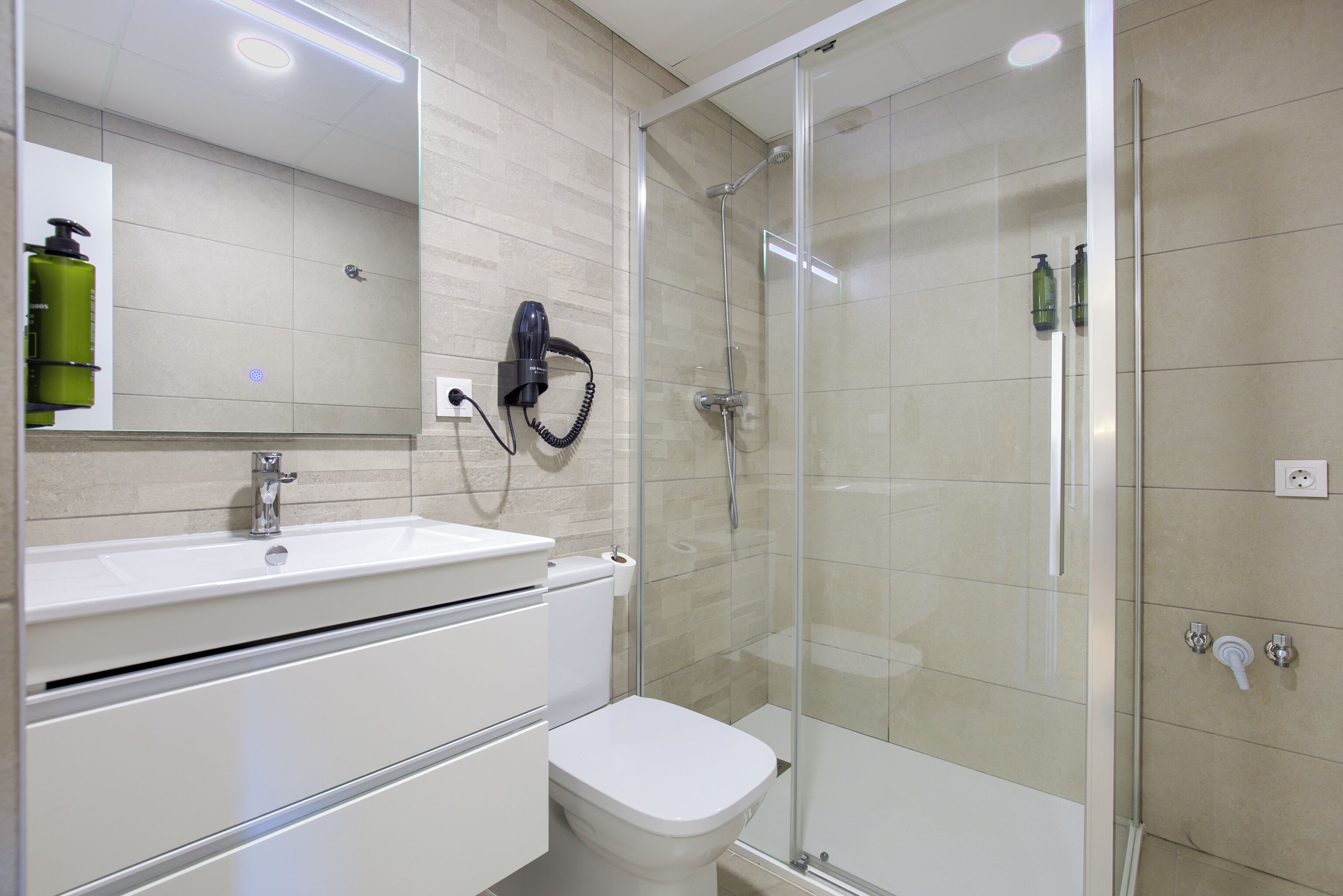 Un baño moderno con ducha envuelta en vidrio, un lavabo blanco y un inodoro.