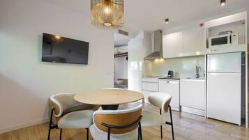 A modern kitchen with white cabinets, a microwave, a refrigerator, and a dining area with a round table and four chairs.