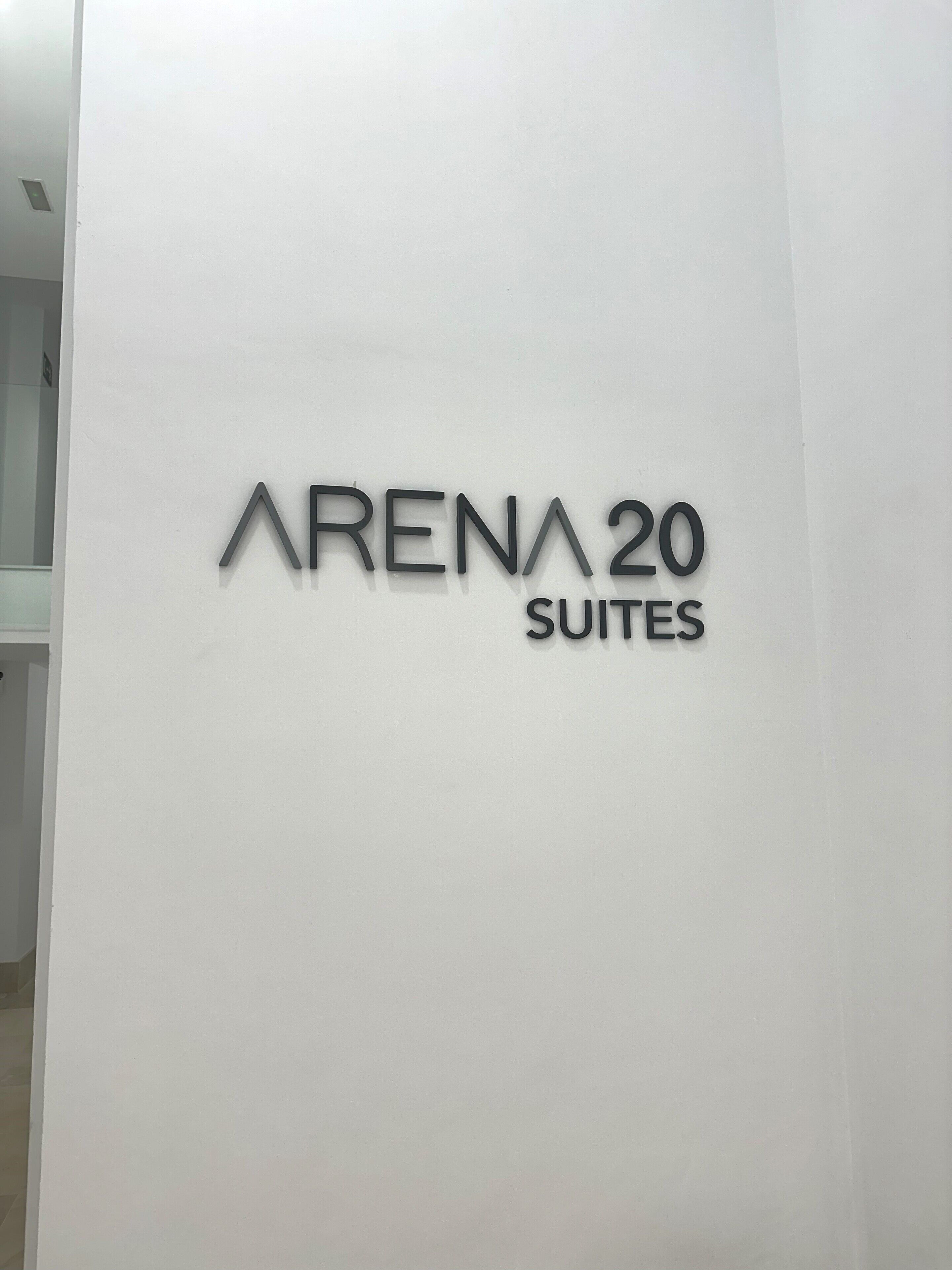 Un letrero que dice "ARENA 20 SUITES" sobre una pared blanca.