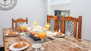 A breakfast table with croissants, orange juice, and coffee cups, a clock on the wall, and a skylight above. - Bumblebee Cottage (Wellington)
