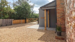 A rustic cottage with a gravel driveway, wooden gate, and a brick wall. - Bumblebee Cottage (Wellington)