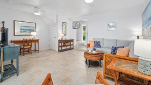 A spacious living room with a sofa, chairs, a dining table, and a television. - Summer Deal Oceanfront Kona Vacation Townhouse with Lanai and Sunsets (Kailua Kona)