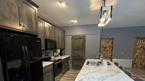 A modern kitchen with dark cabinetry, a marble countertop, and a central island with seating. - Big Chip - 2 is in the heart of the Chippewa Flowage 20 minutes from Hayward, WI (Hayward)