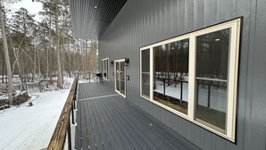 A deck with a railing, a chair, and a view of a snowy forest. - Big Chip - 2 is in the heart of the Chippewa Flowage 20 minutes from Hayward, WI (Hayward)