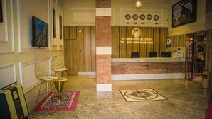 Un'area della reception di un hotel con una scrivania in legno, una sveglia e un quadro appeso al muro.