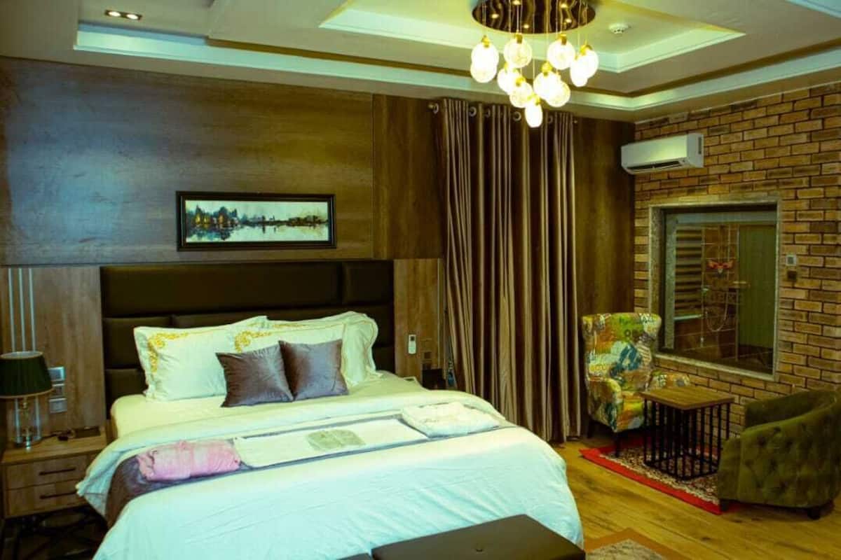 A bedroom with a large bed, a chair, a small table, and a mirror on the wall.