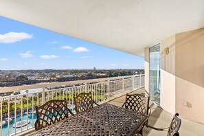 A balcony with a view of a swimming pool and distant buildings.