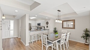 A modern kitchen with white cabinets, a central island, and a dining area with a table and chairs.