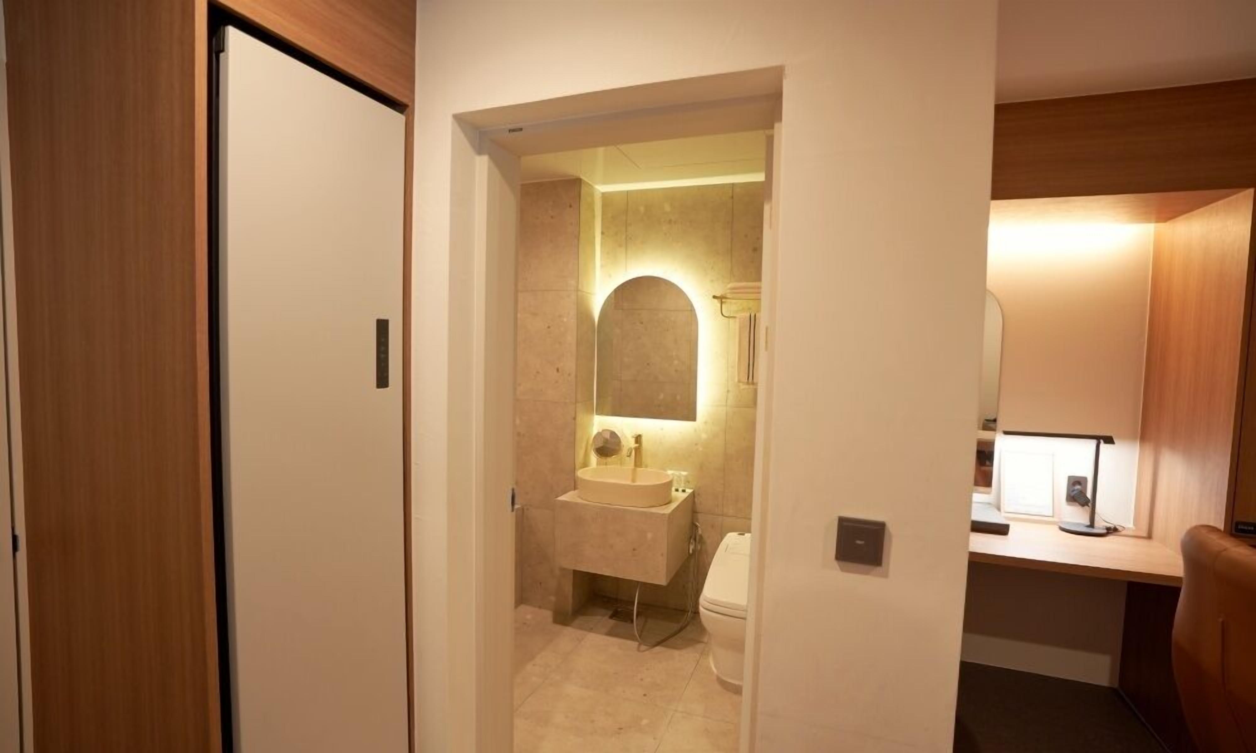 A compact bathroom with a sink, mirror, and toilet.