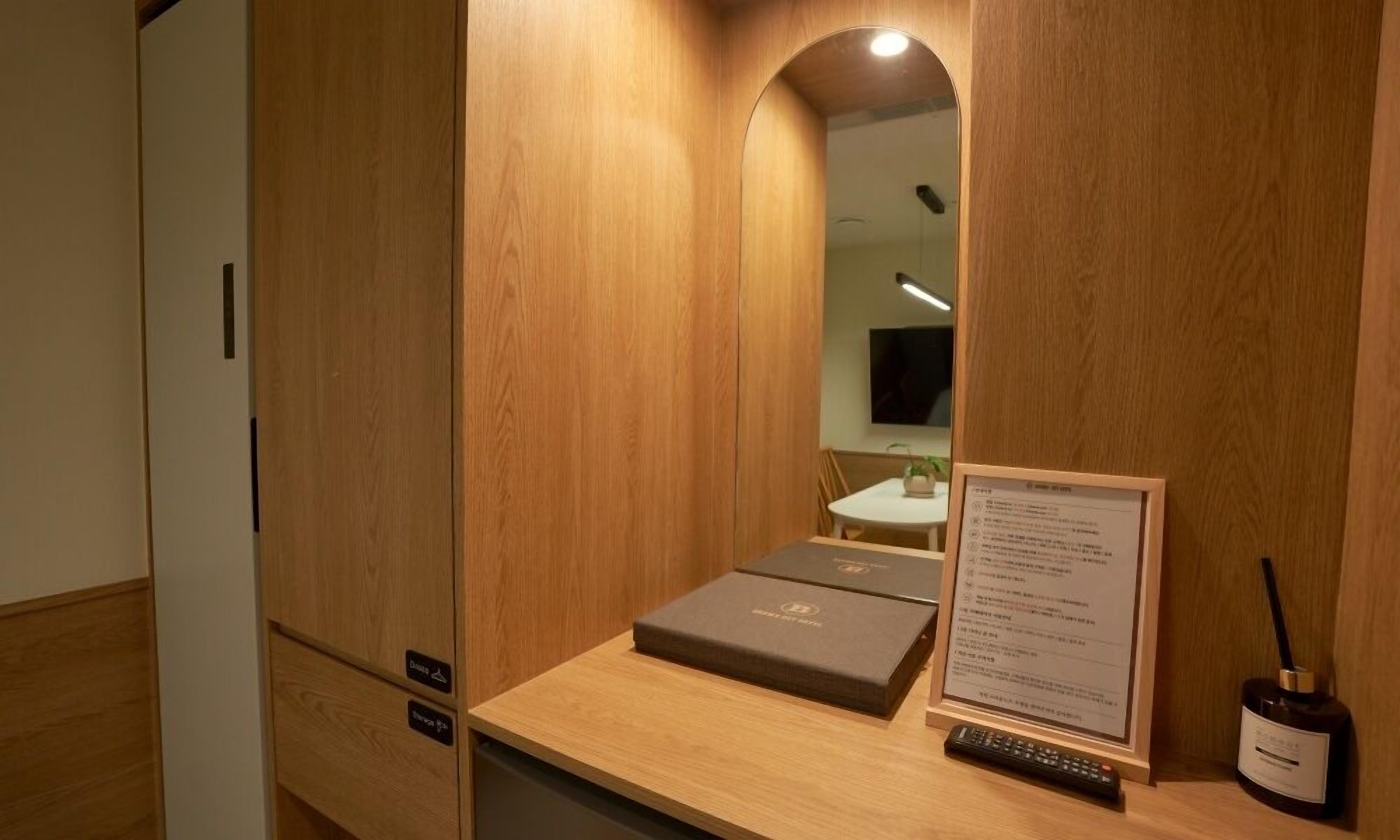 Una habitación con estructura de madera, un escritorio, un control remoto y una botella.