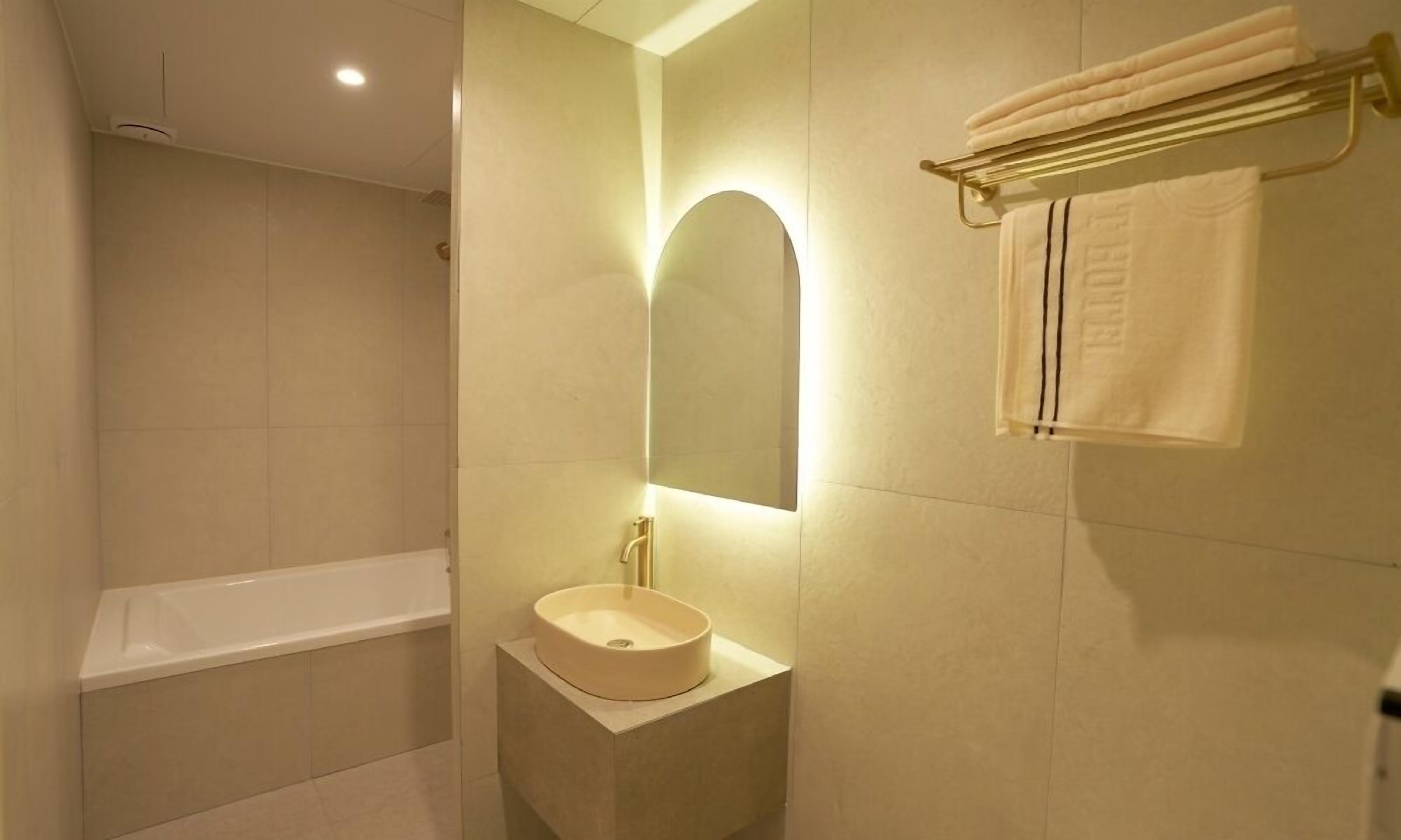 A modern bathroom with a bathtub, a sink, a mirror, and a towel rack.