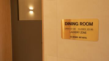 Señal que indica que el comedor está abierto de 7:00 a 23:00 y es una zona de lavandería en el Hotel Brown - Dot.