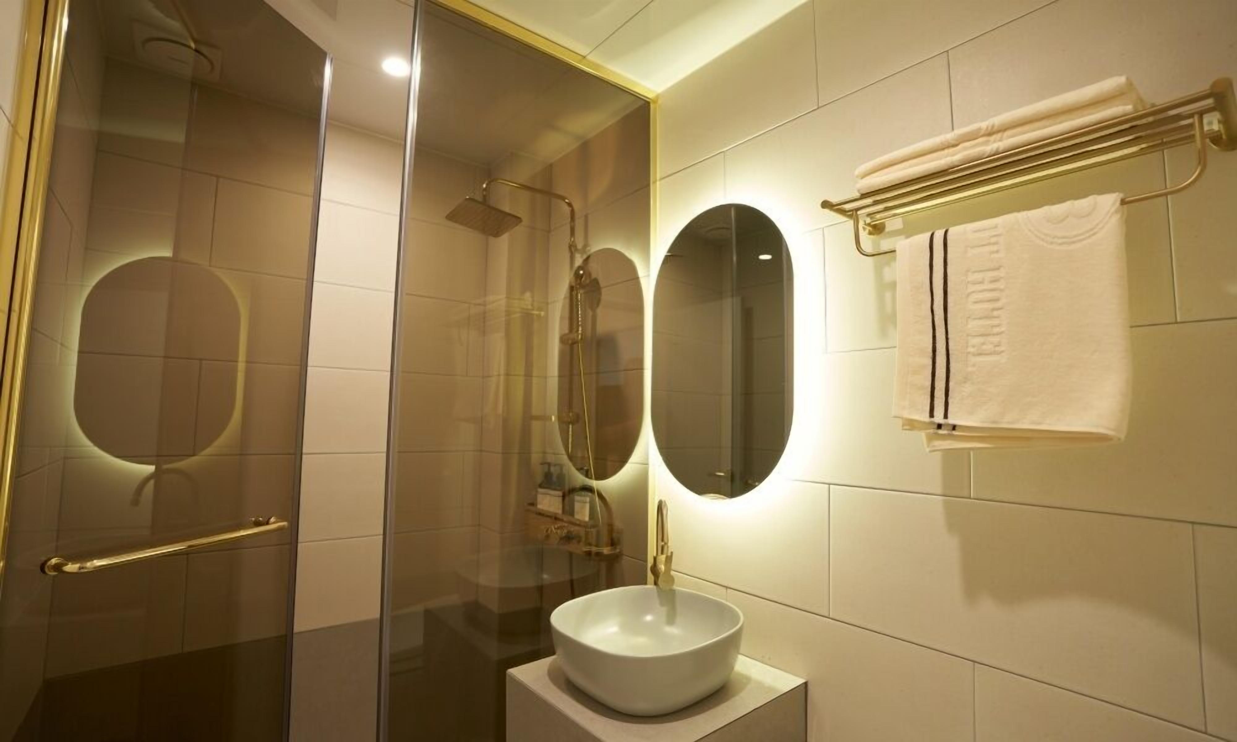 A modern bathroom with a glass-enclosed shower, a white sink, and a towel rack.