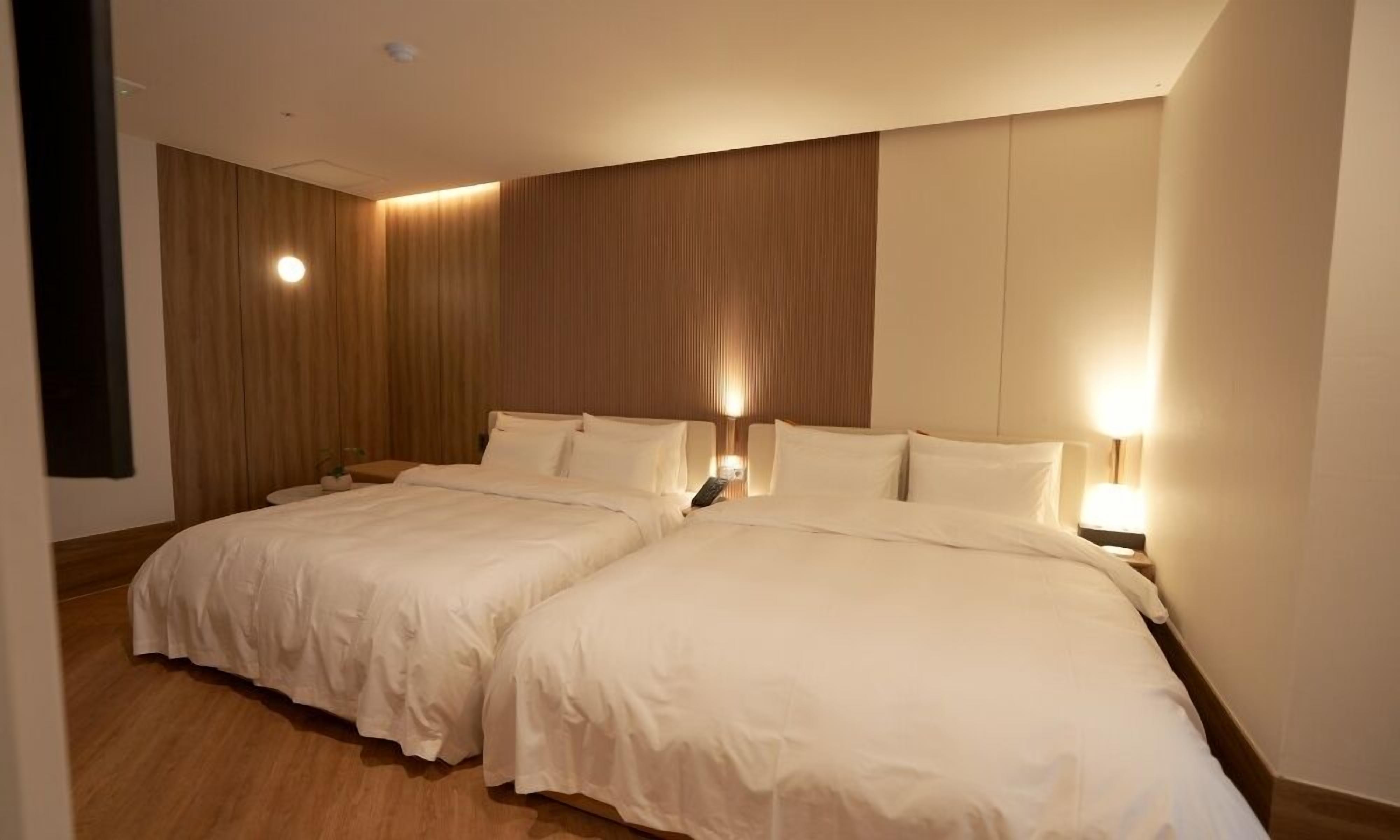 Una habitación de hotel con dos camas, paneles de madera en las paredes y lámparas junto a las camas.