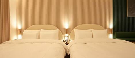 Habitación de hotel con dos camas, una mesita de noche, una lámpara de pared y una pared de acento verde.