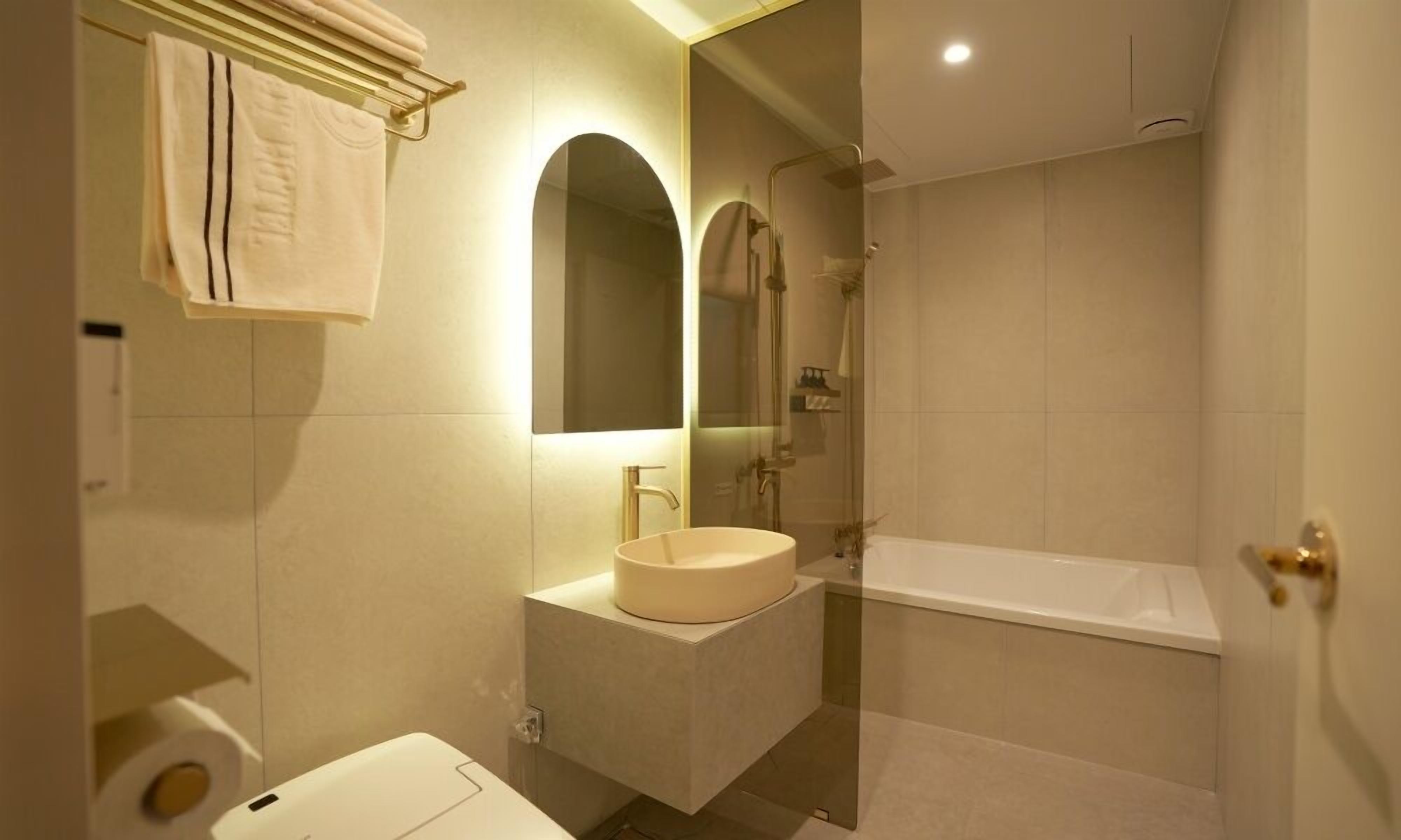 A modern bathroom with a sink, mirror, and bathtub.