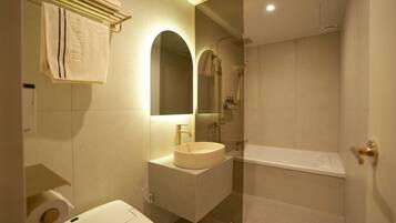 A modern bathroom with a sink, mirror, and bathtub.