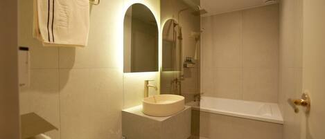 Un baño moderno con lavamanos, espejo y bañera.